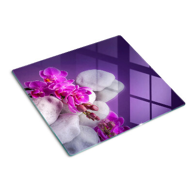 Glazen snijplanken Orchideeënbloemen op een achtergrond van stenen