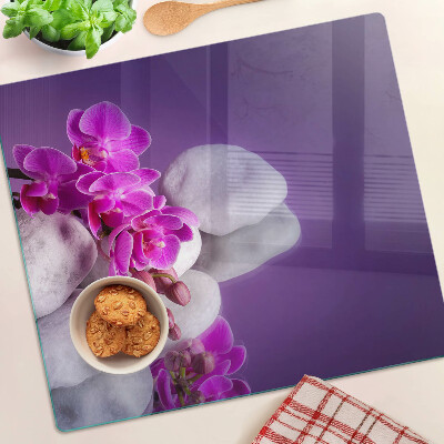 Glazen snijplanken Orchideeënbloemen op een achtergrond van stenen