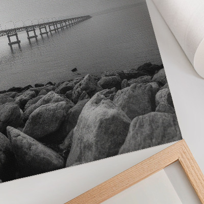 Wandposter Vreedzaam landschap, brug, rotsachtig strand, grijze lucht