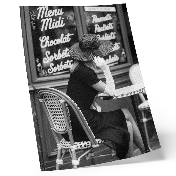 Poster Een vrouw met een hoed op aan een tafel in een café.