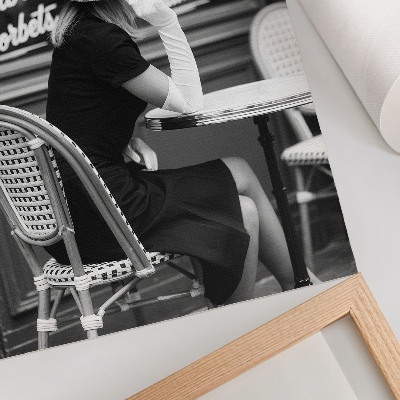 Poster Een vrouw met een hoed op aan een tafel in een café.