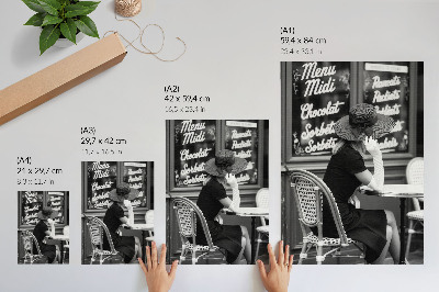Poster Een vrouw met een hoed op aan een tafel in een café.