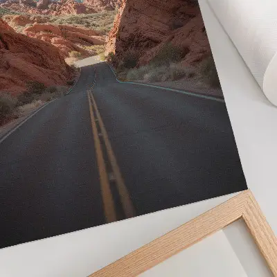 Poster met weg door rotsachtig berglandschap onder een blauwe lucht