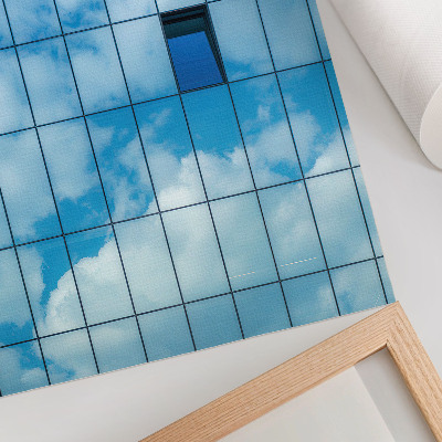 Wandposter Een glazen gevel die de lucht en wolken weerspiegelt.