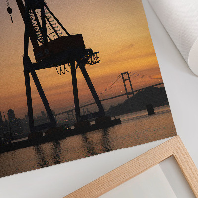 Wandposter Silhouet van een industriële kraan bij zonsondergang op een brug