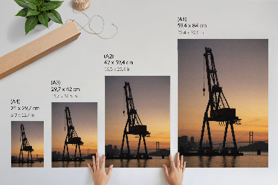 Wandposter Silhouet van een industriële kraan bij zonsondergang op een brug