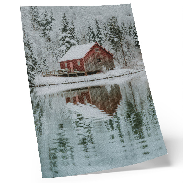 Wandposter Een rood huisje tussen besneeuwde bomen aan het water.