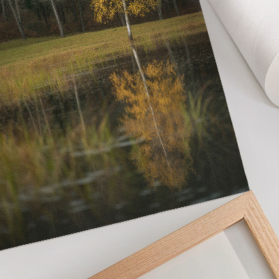 Wandposter Een gouden boom tegen de achtergrond van een donker bos en een meer.