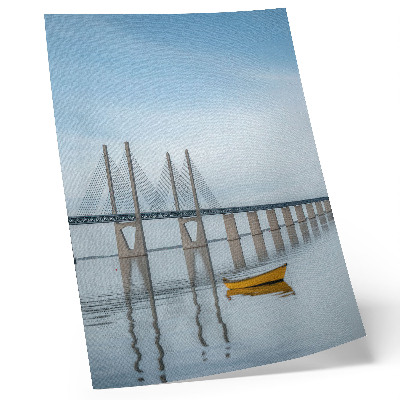 Poster Een brug tegen de hemel en het water met een gele boot.