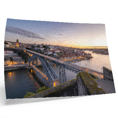 Poster De brug tegen de achtergrond van de ondergaande zon en de stad.