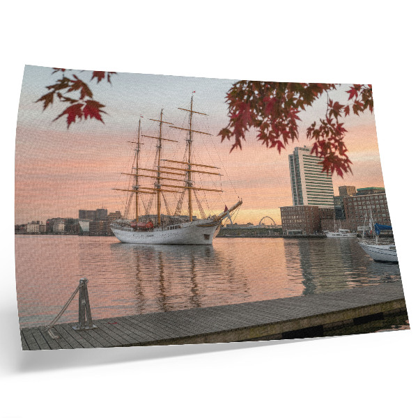 Poster Een zeilschip bij zonsondergang, een vredig panorama van de stad.