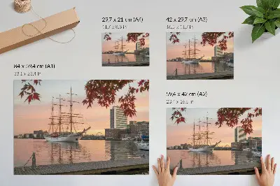 Poster zeilschip bij zonsondergang met een vredig stadsgezicht