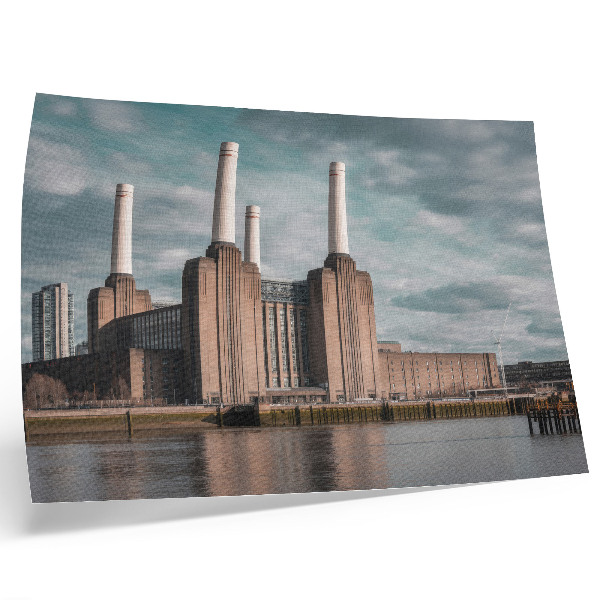 Stijlvolle wandposter Een indrukwekkend gebouw met schoorstenen boven de rivier.