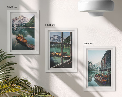Set van ingelijste schilderijen Uitzicht op een bergmeer met boten en een huis aan het water.