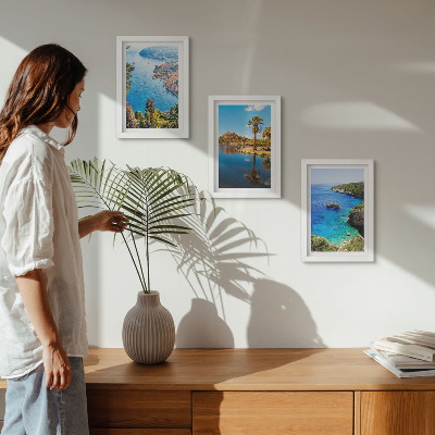 Set van ingelijste schilderijen Uitzicht op zee met palmbomen en blauw water.