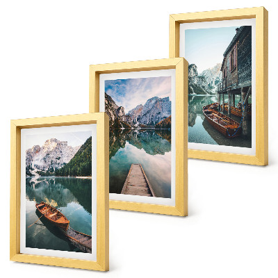 Set van ingelijste schilderijen Een meer in de bergen met bootjes en een houten hut.