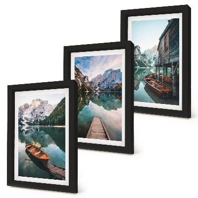 Set van ingelijste schilderijen Een meer in de bergen met bootjes en een houten hut.